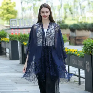 Détail de scène en extérieur montrant le châle kimono en dentelle bleue avec motifs floraux.