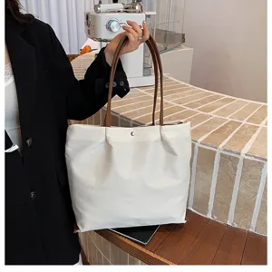 Detailed shot of women's large capacity white tote bag with brown shoulder straps for commuting.