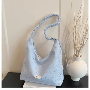 Light blue hobo shoulder bag for women with star print, slouchy design, and chic ruffled strap.