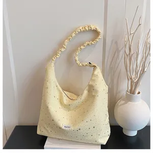 Detail view of yellow starlight printed slouchy shoulder bag with scrunchie strap and label.