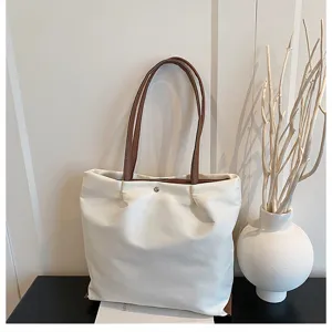 Detailed view of the casual canvas tote bag with brown leather handles and spacious interior.