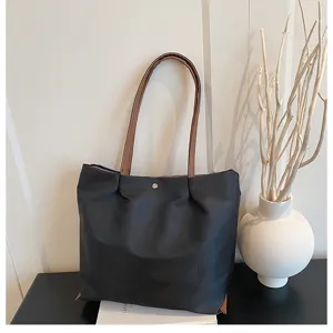Detailed close-up view of black oxford cloth tote bag with brown straps in elegant room setting.