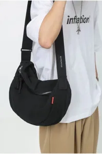 Detailed view of the casual black canvas dumpling shoulder bag, showing strap and zipper.