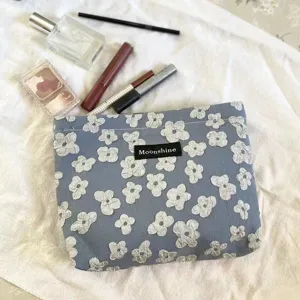 Detailansicht der schicken blauen Kosmetiktasche mit floralem Jacquard-Muster und Label.