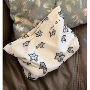 Detailaufnahme der Leinen-Kosmetiktasche mit schwarzem Blumenmuster und kleinem Stoffetikett.