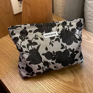 Nahaufnahme der schwarz-weißen Kosmetiktasche mit Blumenmuster, Jacquard-Stoff und Design.