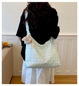 Light blue polka dot canvas tote bag with ruffled strap and cute puppy pendant for daily commute.