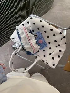 Detail shot of white polka dot tote bag, casual large capacity commuter shoulder bag for women.