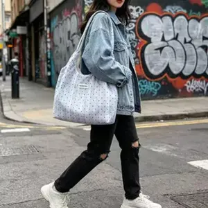 Street style detail view of large capacity canvas shoulder tote bag with cute pattern.