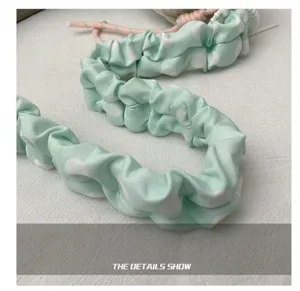 Detailed view of the mint green polka dot gathered shoulder strap, soft fabric accessory.