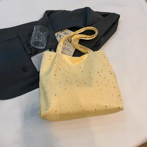 Detailed close-up of the yellow canvas tote bag with shiny silver stars, styled for daily wear.
