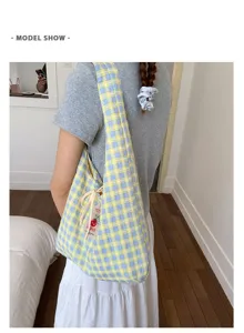 Detail view of the yellow and blue plaid canvas shoulder bag showing pattern and strap.