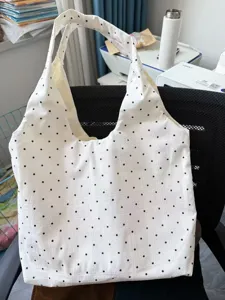 Detail view of a white canvas tote bag with black polka dots, casual daily shoulder bag style.