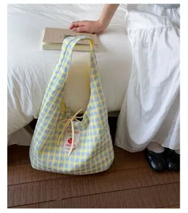 Detail shot of a fresh Japanese style plaid canvas tote bag with drawstring closure in a room.
