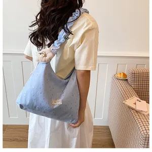 Detailed view of blue star print tote bag featuring ruffled shoulder strap and charm.