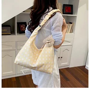 Yellow polka dot canvas shoulder bag lifestyle detail with pleated strap and cute puppy.