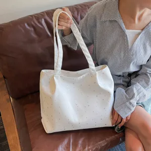 Detail view of a white canvas tote bag featuring subtle star patterns for daily commuter use.