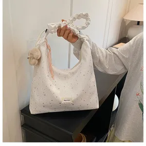 Detail view of the star print tote bag featuring a cute plush bear charm and gathered handle.