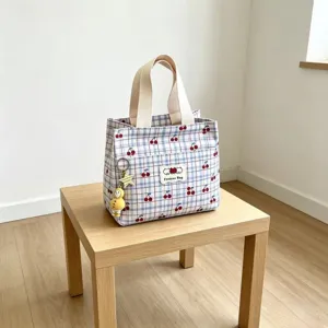 Vista dettagliata della borsa cosmetica a quadri e ciliegie con manici e simpatico ciondolo.