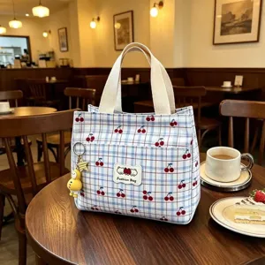 Vista dettagliata della borsa cosmetica a quadri con ciliegie e un grazioso ciondolo a forma di anatra.