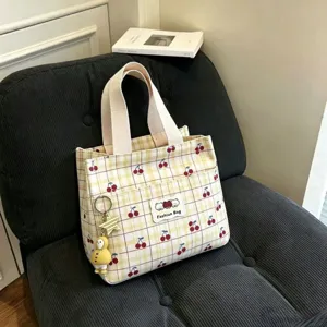 Vista dettagliata della borsa cosmetica in tela a quadri gialli con ciliegie e manici.