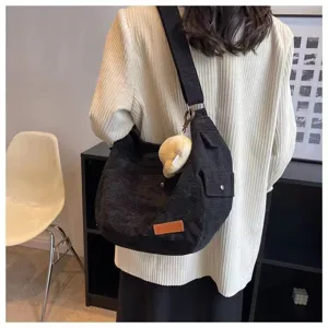 Detail view of the black corduroy shoulder bag showing fabric texture and cute pendant charm.