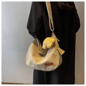 Detailed view of women's retro corduroy shoulder bag with cute plush pendant for daily commute.