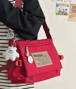 Red canvas messenger bag detailed view, showing retro style flap and textured label.