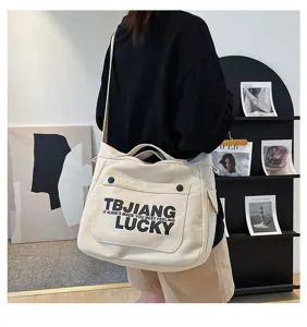 Detailed view of large canvas tote bag, beige shoulder crossbody bag with black letter print.