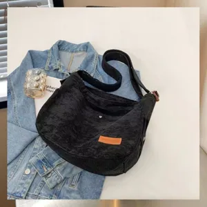 Detailed view of the black corduroy shoulder bag styled with a denim jacket on white background.