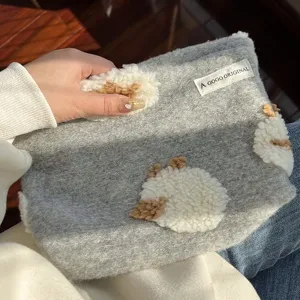 Detailansicht der grauen Kosmetiktasche mit flauschiger Schaf-Applikation und weicher Textur.