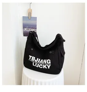 Detailed view of black canvas shoulder bag with front white letter print, casual style.