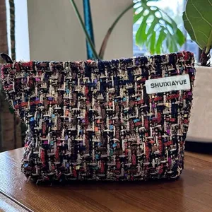 Detailansicht der stilvollen Tweed Kosmetiktasche mit buntem Webmuster und Etikett.
