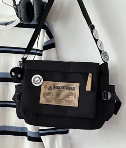 Detailed view of a black canvas messenger bag featuring vintage style, large capacity, and cool badges.