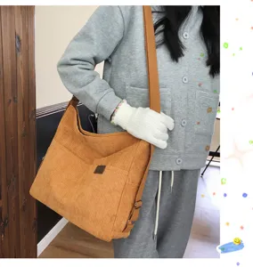 Vue détaillée du sac bandoulière marron en velours côtelé, montrant grande capacité et poche.
