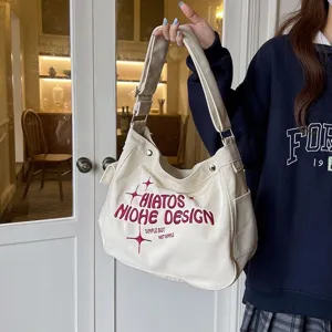 Detail view of casual canvas shoulder bag with embroidered lettering and spacious interior.