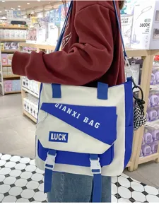 Vue détaillée du sac bandoulière en toile bicolore bleu et blanc avec poche à rabat.