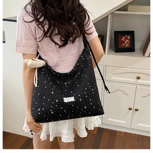Detail shot of a casual black star print tote bag with large capacity and cute plush pendant.