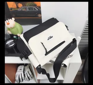 Black and white nylon messenger bag detail, featuring contrast color flap and front zipper pocket.