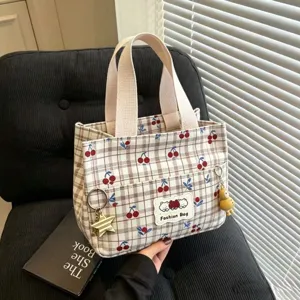 Vista dettagliata della borsa cosmetica in tela a quadri e ciliegie con manici e ciondoli.