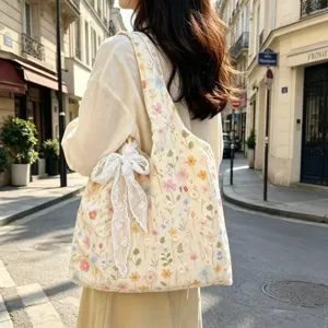 Detail view of floral embroidered canvas shoulder bag with white lace bow decoration