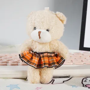 Primo piano dettagliato di una mini bambola di peluche con gonna a quadri arancione, accessorio.