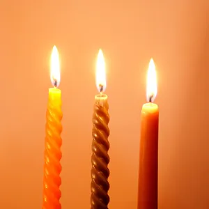 Primo piano di candele di cera accese con design a spirale e liscio, dettagli caldi.