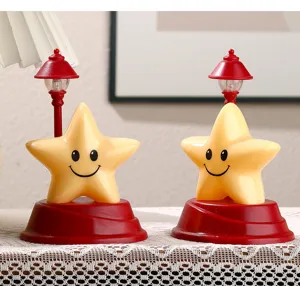 Simpatica luce notturna a stella sorridente con base rossa e mini lampione per la scrivania.