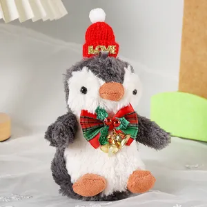 Primo piano del ciondolo pinguino di peluche con cappello di Natale rosso e fiocco con campana.