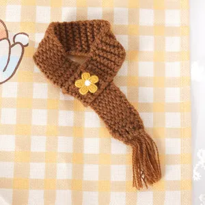 Mini gebreide sjaal detailweergave, bruin pluche pop accessoire met gele bloemdecoratie.