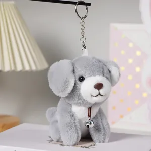Primo piano del simpatico portachiavi con cagnolino in peluche grigio e campanello di metallo.