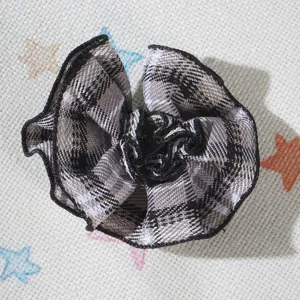 Primo piano dettagliato di un fiore in tessuto a quadri bianco e nero per accessori bambola.