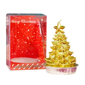 Candela dorata a forma di albero di Natale con scatola regalo rossa e base in foglia.