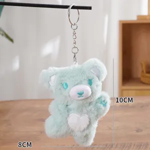 Cute mint green plush bear keychain detail shot, soft fuzzy fabric with white heart motif, 10cm.